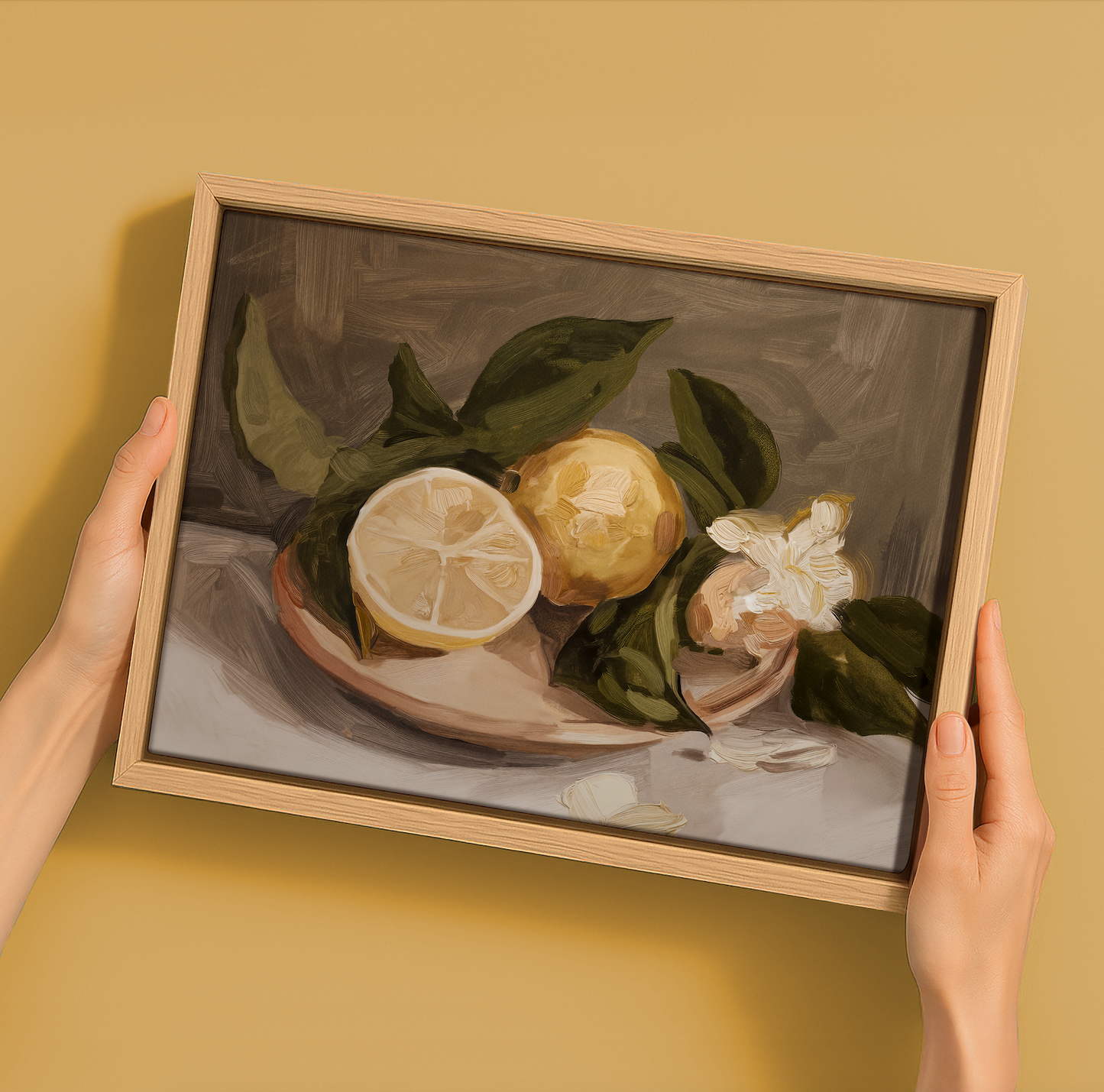 Hands holding a Darren Palmer Lemon Harvest - Oak Box Frame Canvas (22.5x30, Landscape), featuring lemons with green leaves and white flowers—farmhouse wall art ideal for any room.