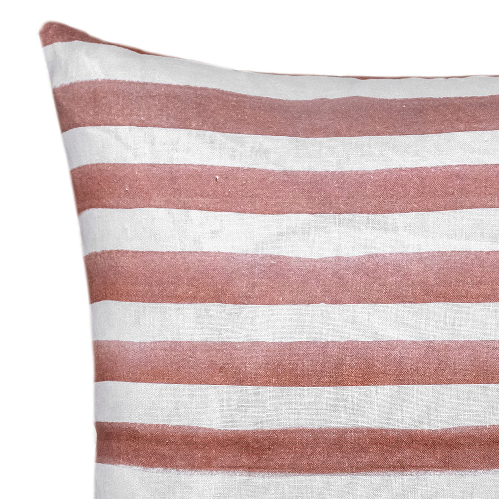 The Rumi Striped Terracotta Linen Cushion With Feather Insert (50x50cm) by Urban Road features hand-painted, uneven reddish-brown stripes on white—ideal for adding a modern boho touch to your decor.