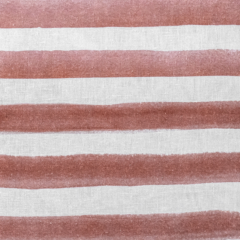 The Rumi Striped Terracotta Linen Cushion With Feather Insert (50x50cm) by Urban Road features hand-painted, uneven reddish-brown stripes on white—ideal for adding a modern boho touch to your decor.