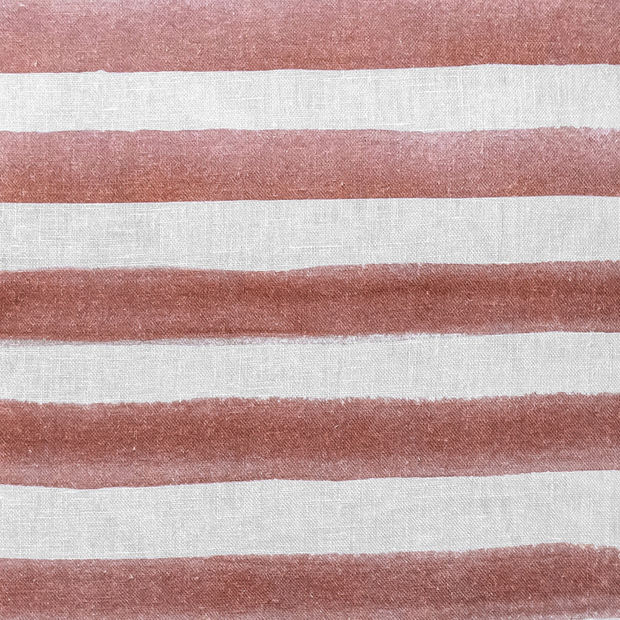 The Rumi Striped Terracotta Linen Cushion With Feather Insert (50x50cm) by Urban Road features hand-painted, uneven reddish-brown stripes on white—ideal for adding a modern boho touch to your decor.