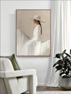 The "Texas Hold ‘Em - Oak Box Frame Canvas - 90x120 - Portrait" by Urban Road showcases equestrian art of a woman in a white dress and hat riding side-saddle, displayed above a white armchair beside a potted plant and white curtains.