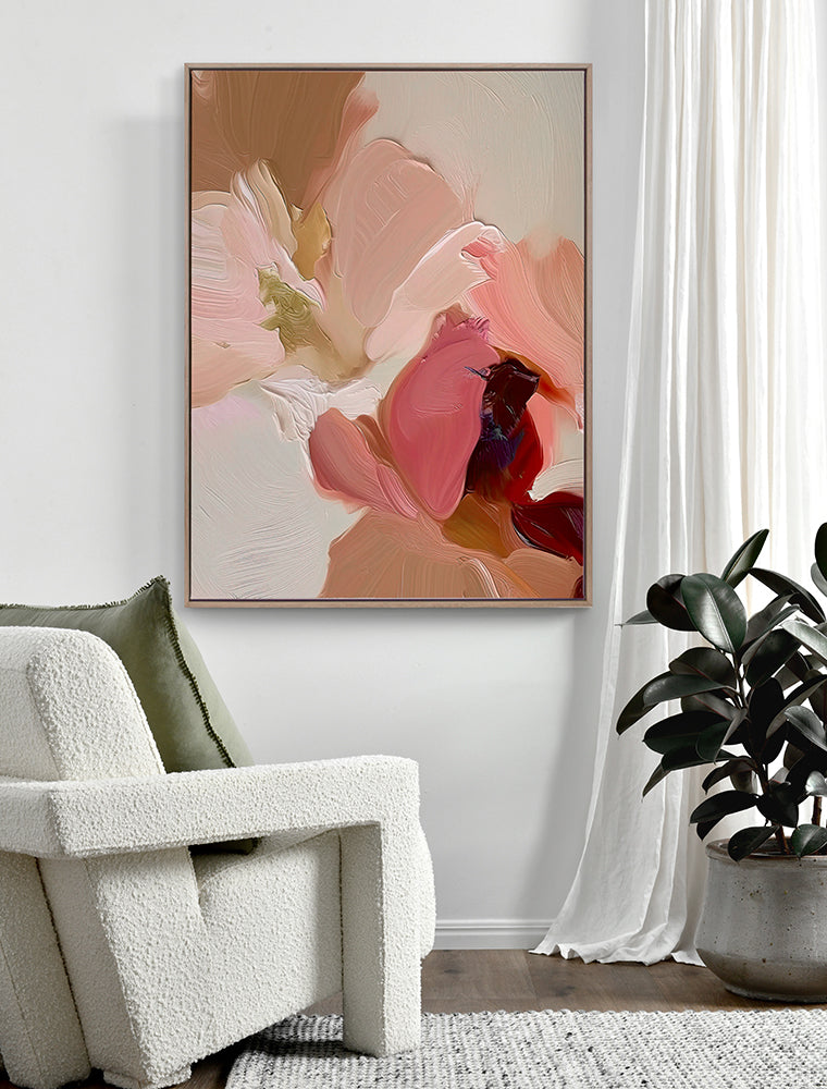 A modern living room with a textured white armchair, green pillow, potted plant, sheer curtains, and Urban Road’s Petals III Oak Box Frame Canvas (90x120) art print in warm pink and beige tones displayed on the wall.