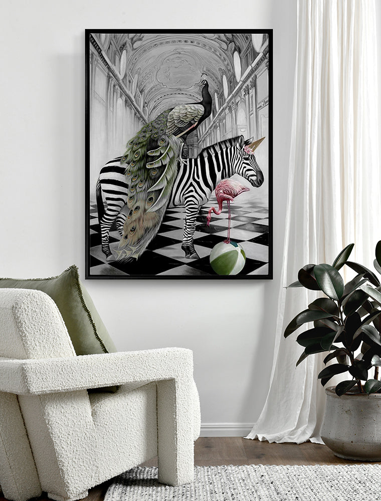 A modern living room showcases Urban Road’s "In Wonderland" (Black Box Frame Canvas, 120x90, Portrait), artfully depicting a zebra with a peacock, a flamingo, and a green-striped ball on a checkered floor, styled with a white armchair and green pillow.