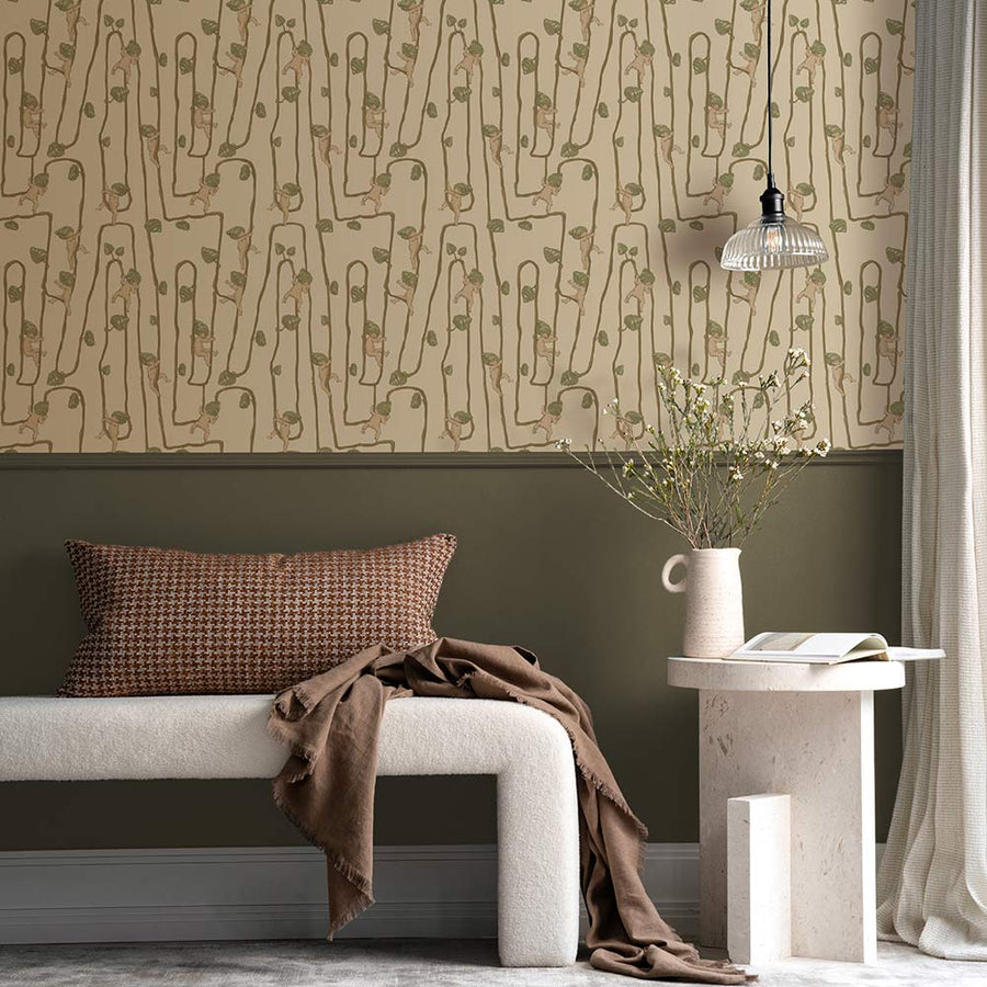 A young girl sits on a rug in a modern living room with a fluffy dog, plush toys, and cushions, all set against the Urban Road Giggly Bush Babies Wallpaper in soft olive green, adding a playful touch to the space.
