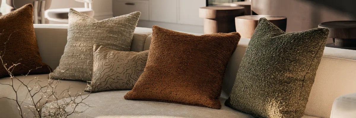 Inviting sofa adorned with richly textured cushions in warm earth tones, complemented by minimalist decor and greenery.