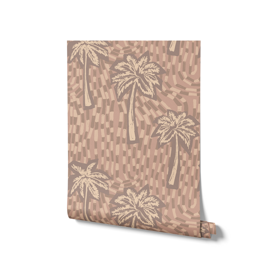 Soft pink wallpaper with cream-toned palm tree silhouettes and abstract tile-like brush strokes, from the Shatha collection with Urban Road.