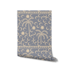 Dusty blue wallpaper with warm cream palm trees, moons, and a decorative woven-style header, from the Shatha collection with Urban Road.