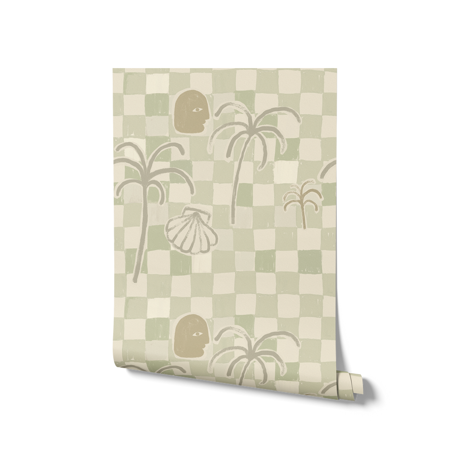 Soft sage green wallpaper with hand-drawn checkered squares, stylised palm trees, a face motif, and a shell illustration, from the Shatha collection with Urban Road.