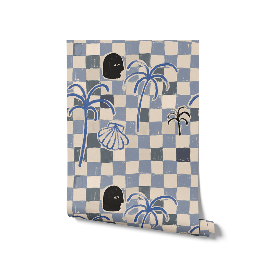 Dusty blue and cream checkered wallpaper featuring bold palms, a dark face profile, and a sketched shell motif, from the Shatha collection with Urban Road.