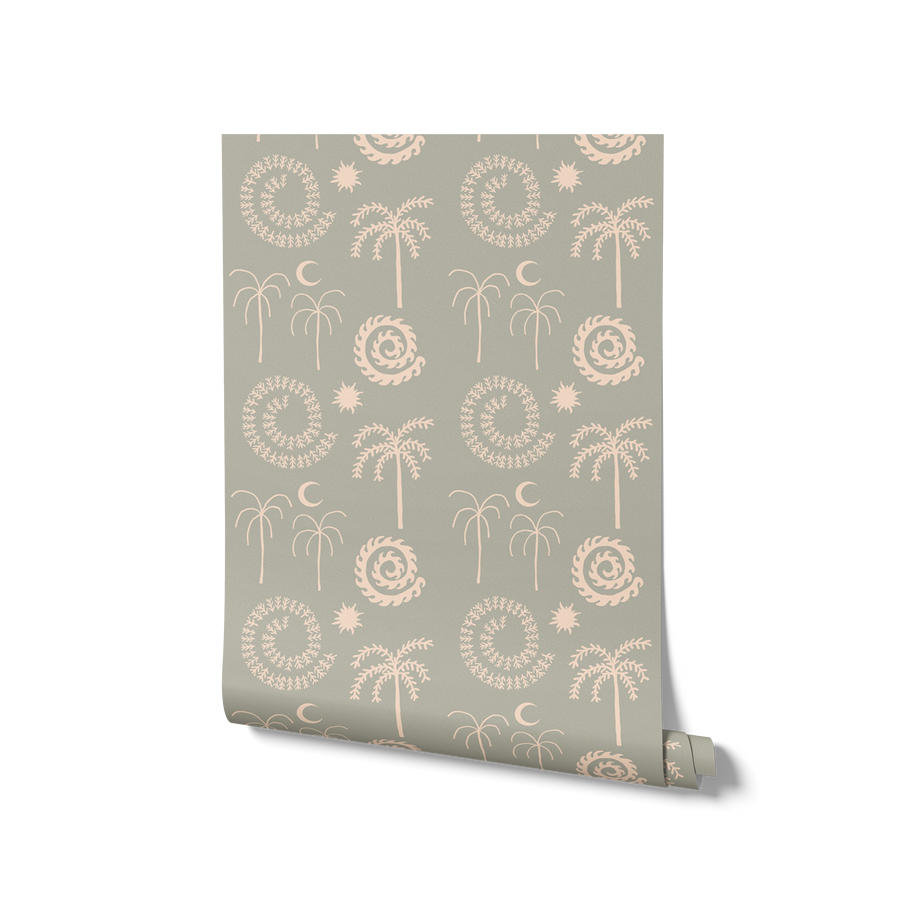 Mint green wallpaper with hand-drawn palm trees, swirling sunburst motifs, and crescent moons in pale cream, from the Shatha collection with Urban Road.