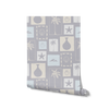 Light blue wallpaper with soft cream coastal illustrations in a patchwork of framed motifs including palms, seashells, and waves, from the Shatha collection with Urban Road.