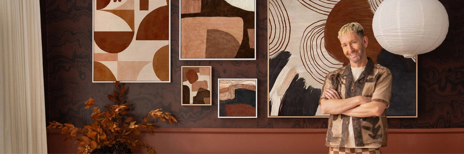 Tim Neve standing in front of a brown gallery wall featuring five abstract artworks, styled with earthy decor tones.