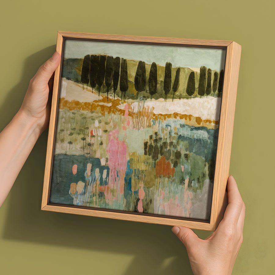 Two hands hold the Urban Road "Finding Your Way III" canvas (30x30, Oak Box Frame), featuring an abstract landscape with vertical tree forms and soft green, pink, and blue tones on a muted olive background.