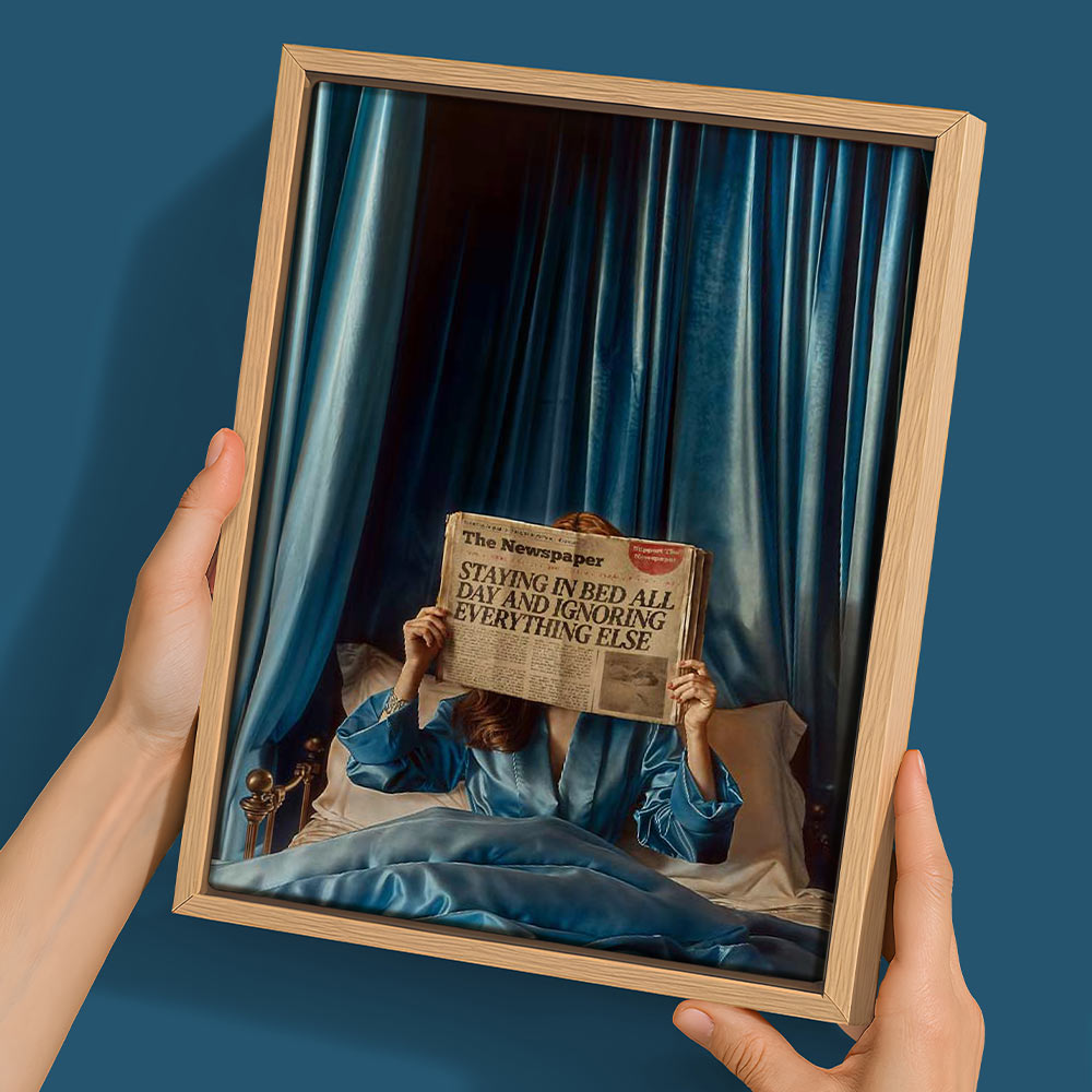 A person in blue pajamas sits on a blue-sheeted bed holding a newspaper that reads "STAYING IN BED ALL DAY AND IGNORING EVERYTHING ELSE" in Urban Road's Morning Gossip, a 22.5x30 oak box frame canvas—perfect as mid-century modern wall art.