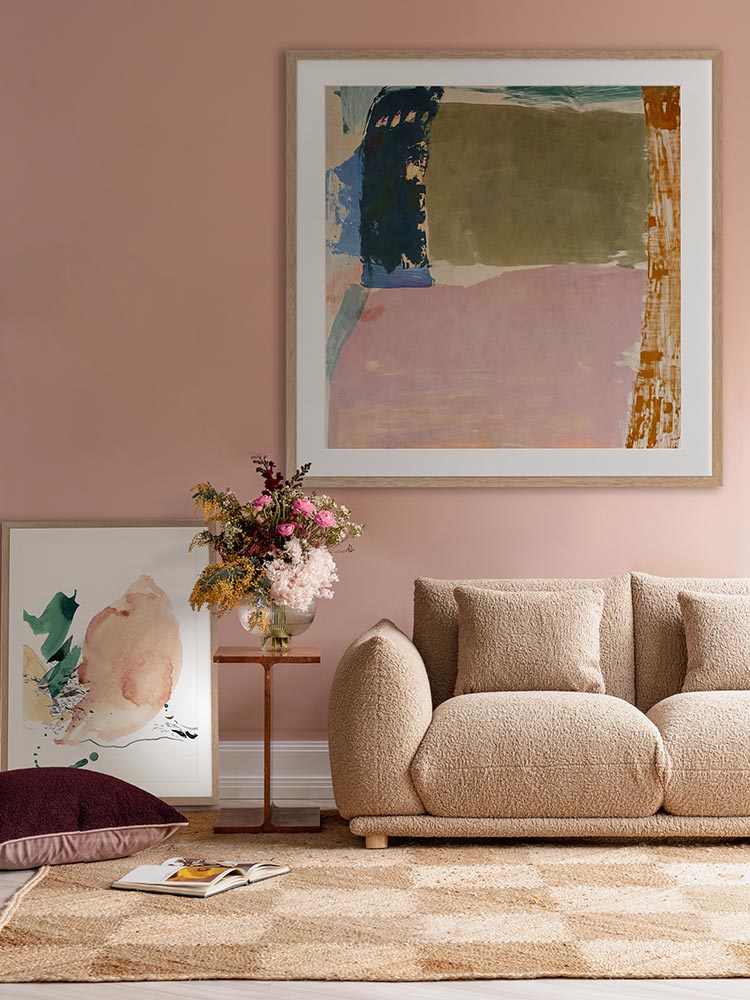 Desert Blush I abstract wall art print against a dark blue wall styled with seating furniture, decor and a checkered rug.