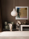 Desert Blush II abstract wall art print styled with neutral seating and decor, a checkered rug, and a dark brown wall.