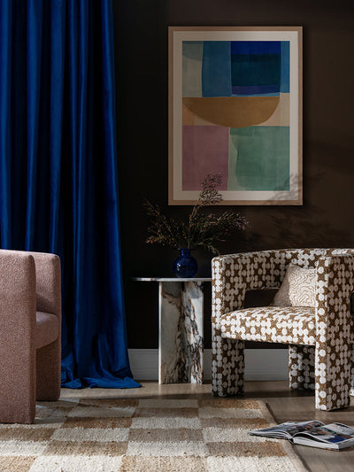 Sun Tiles I colourful abstract art print above a blue armchair with white curtains and modern decor in a bright room.