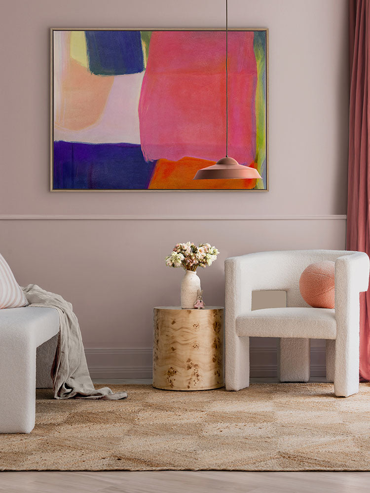 Neon Dreams abstract artwork adds bold colour above a neutral armchair and checkered rug in a soft pink and timber setting.