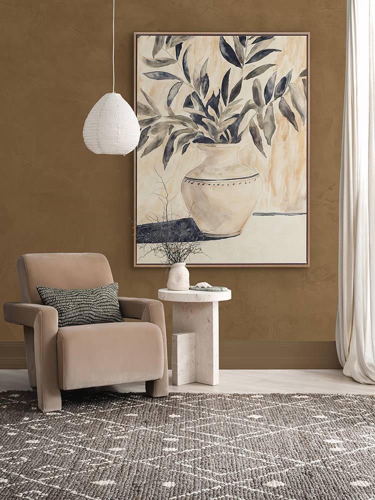Golden Vase botanical artwork styled above a beige armchair in a caramel-toned living space with a grey rug and soft drapery.