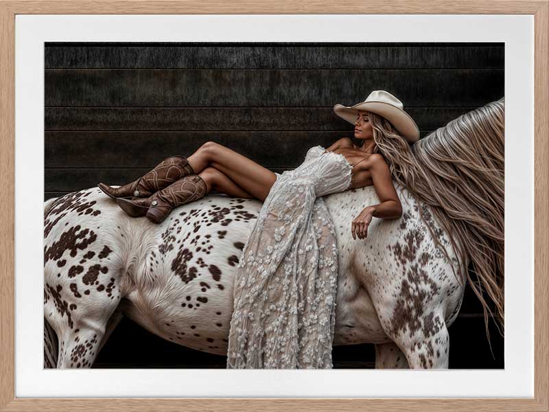 Glamorous photographic horse wall art featuring a woman in a cowboy hat and boots relaxing on a horse in earthy tones.