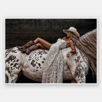 Glamorous photographic horse wall art featuring a woman in a cowboy hat and boots relaxing on a horse in earthy tones.