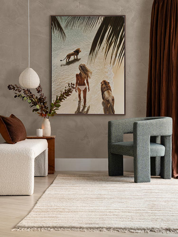 Lioness artwork in a neutral living room with green armchair, white love seat, and dark red-brown curtains and cushions.