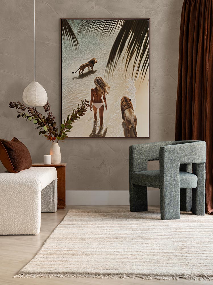 Lioness artwork in a neutral living room with green armchair, white love seat, and dark red-brown curtains and cushions.