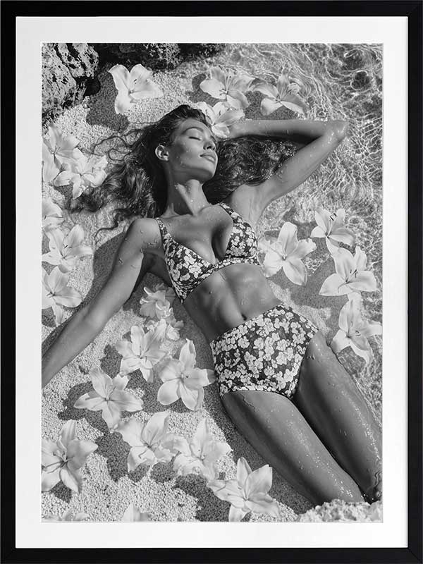 Monochrome photographic artwork of a serene woman lounging amid flowers in water, giving all the luxurious vibes.