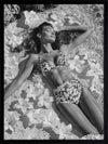 Monochrome photographic artwork of a serene woman lounging amid flowers in water, giving all the luxurious vibes.