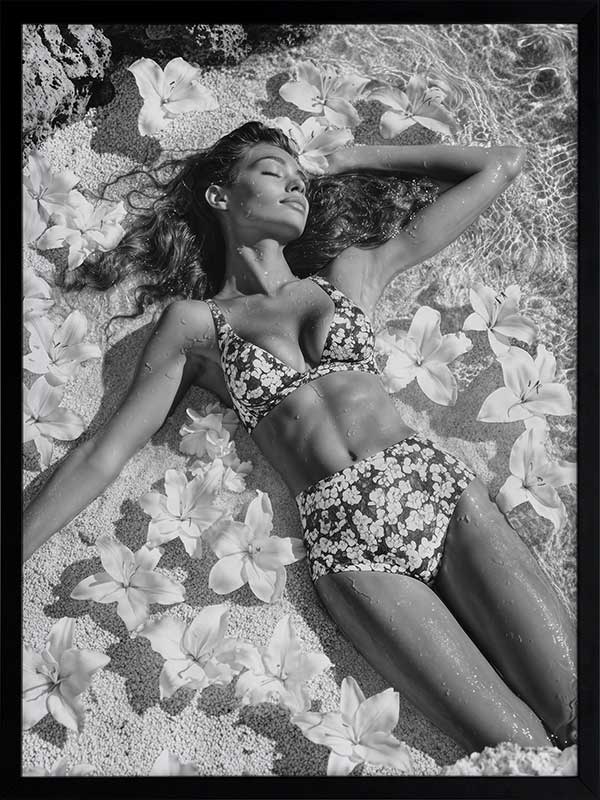 Monochrome photographic artwork of a serene woman lounging amid flowers in water, giving all the luxurious vibes.