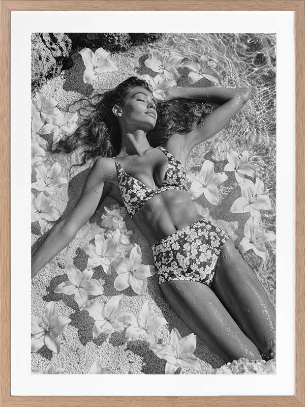 Monochrome photographic artwork of a serene woman lounging amid flowers in water, giving all the luxurious vibes.