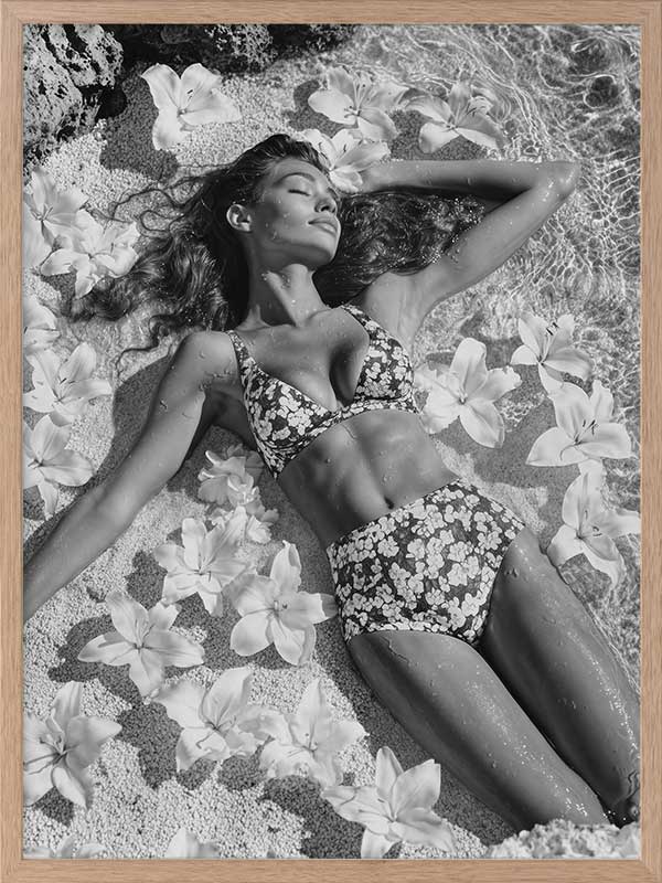 Monochrome photographic artwork of a serene woman lounging amid flowers in water, giving all the luxurious vibes.