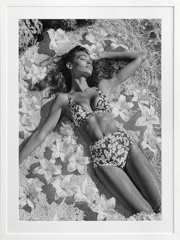 Monochrome photographic artwork of a serene woman lounging amid flowers in water, giving all the luxurious vibes.