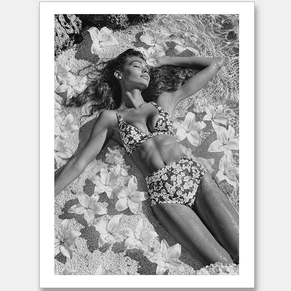 Monochrome photographic artwork of a serene woman lounging amid flowers in water, giving all the luxurious vibes.