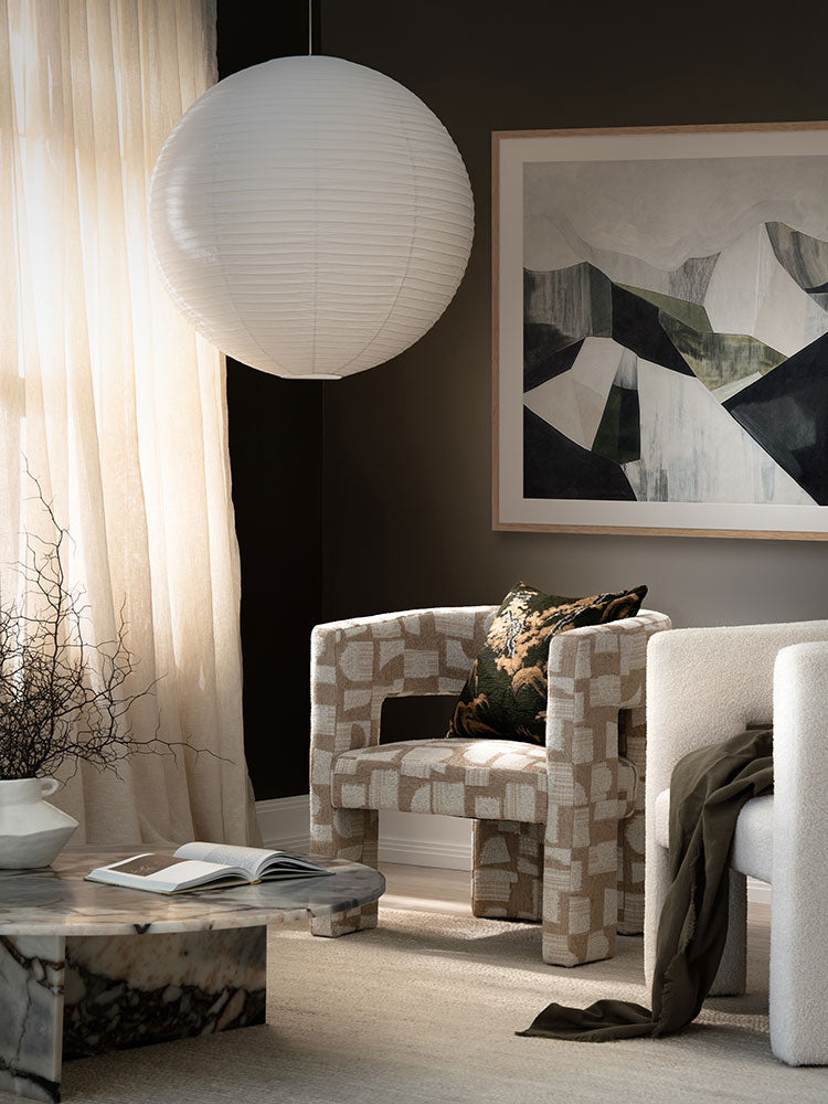 Geometric Landscape II abstract artwork above a tan sofa and green armchair, styled with dried florals and neutral decor.