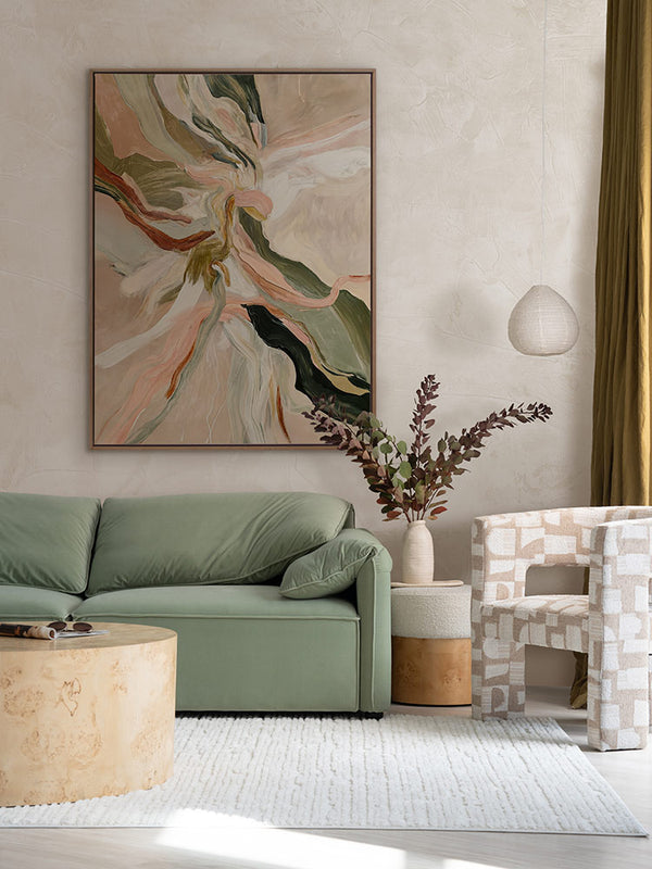 Warm Memories I abstract art above a sage green couch, patterned armchair, white rug and other neutral decor.