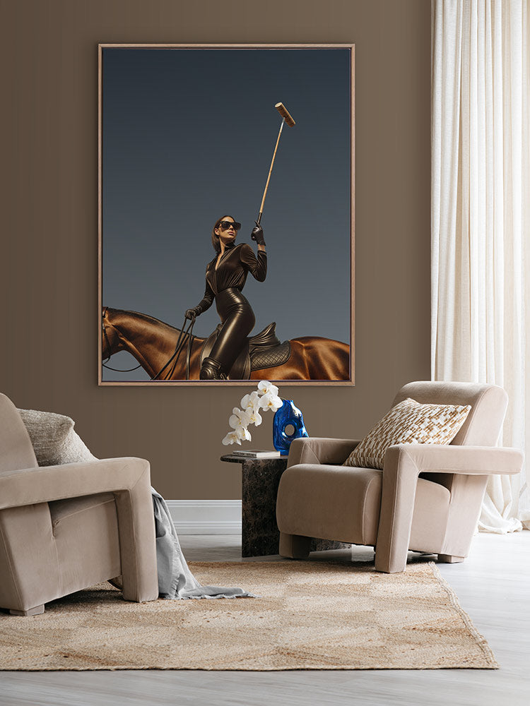 She’s a Polo Player portrait art hanging in a modern lounge with beige armchairs, white curtains and a sculptural side table.