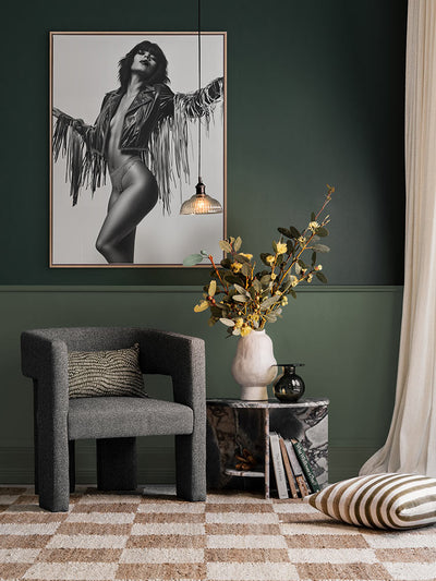 Born to Roam portrait artwork styled above a dark armchair in front of dark green wall, with patterned floor and warm accents.