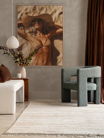 Beach Babe artwork in a neutral-toned space featuring timber floors, sculptural side table, green velvet chair, and sheer curtains.