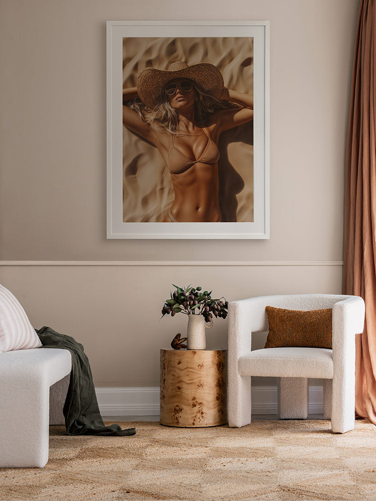 Beach Babe artwork in a neutral-toned space featuring timber floors, sculptural side table, green velvet chair, and sheer curtains.