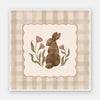 A sweet brown bunny framed by flowers and leaves on a soft green gingham backdrop, from the Little Tails Collection by Urban Road.