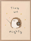 A tiny hedgehog holding a little sword and shield with scattered stars and the phrase “tiny but mighty” in warm neutral browns, from the Little Tails Collection by Urban Road.