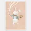 A white bunny holds a paintbrush and palette, sweeping playful painted swirls and star shapes across a pastel pink backdrop, from the Little Tails Collection by Urban Road.