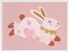 A leaping pink bunny sprinkled with heart patches on a textured blush ground, from the Little Tails collection by Urban Road.