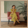Portrait of a woman in yellow stripes sitting offline in a muted room setting, from the Lounging Ladies II collection by Urban Road.