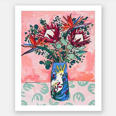 The "Pink Cockatoo Unframed Art Print" by Urban Road features colorful proteas and kangaroo paws in a floral vase set on a green patterned table, with a pink abstract background for vibrant still life decor.