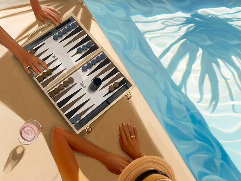 Two people play backgammon by the pool with sunlight and palm shadows. A drink and sunhat add to the scene—the "Backgammon, Anyone Canvas Art Print" by Shaynna Blaze x Urban Road radiates a bright, relaxed summer vibe.
