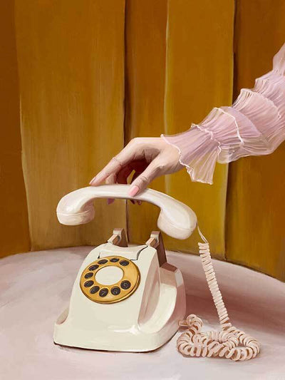 A hand in a sheer, ruffled pink sleeve lifts a vintage cream and yellow rotary phone against gold panels—featured in the Out Of Office Canvas Art Print by Shaynna Blaze x Urban Road.