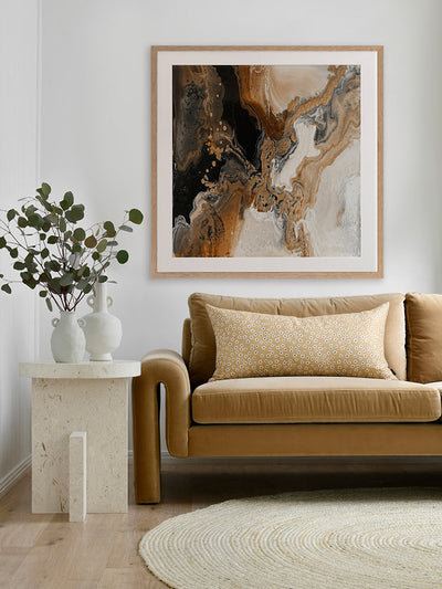 A framed Terrain Tides III art print displayed above a brown armchair in a deep-hued modern living space. The abstract artwork’s rich, earthy tones contrast beautifully with the light walls.