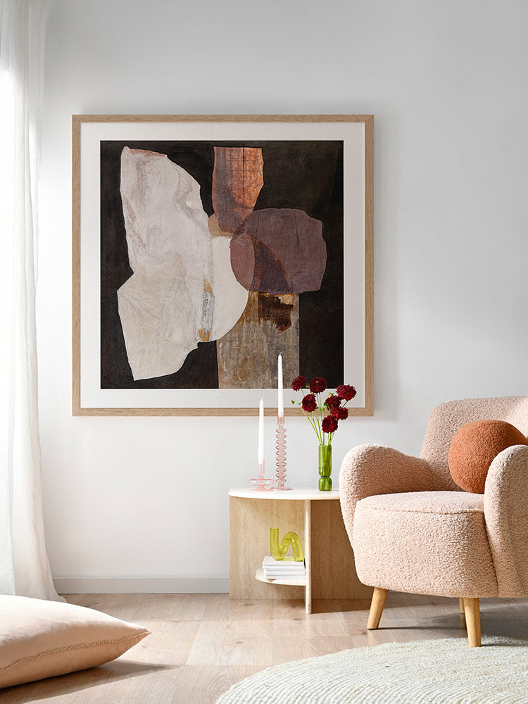 A framed Chiaroscuro II art print displayed above a modern chair in a sophisticated living space with light coloured walls, soft lighting, and minimalist decor.